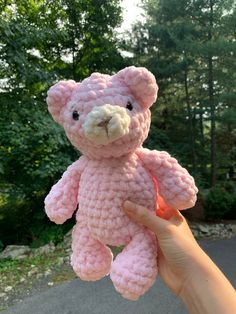 a hand holding a pink crocheted teddy bear