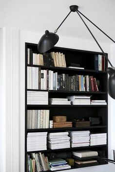 a bookshelf filled with lots of books next to a wall mounted light above it