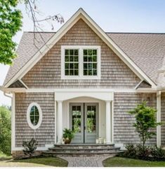 a gray house with white trim and two large windows on the front door is shown