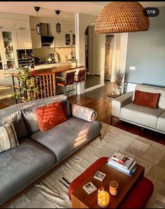 a living room filled with furniture next to a kitchen and dining room table in front of an open floor plan