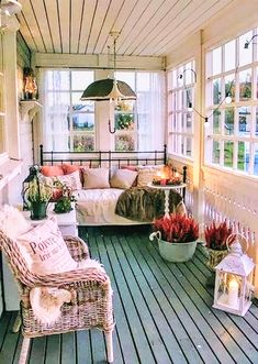 the porch is decorated with wicker furniture and potted plants, along with candles