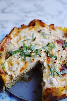 a quiche with one slice missing from it on a blue and white plate