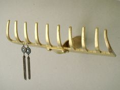 a gold metal rack with earrings hanging from it's sides and a hook on the wall