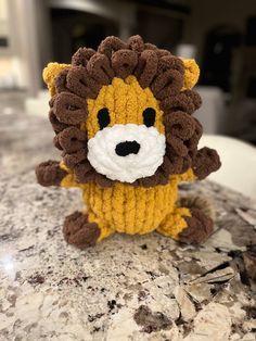 a knitted lion sitting on top of a marble counter with it's eyes closed