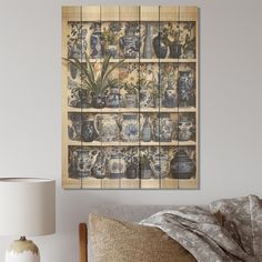 a wall hanging on the side of a bed next to a lamp and vases