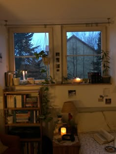 a bedroom with a bed, bookshelf and lamp in front of the window