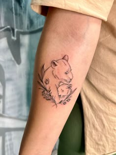 a person with a tattoo on their arm holding a small bear and flower bouquets