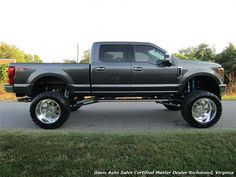 a large gray truck parked on the side of a road next to a grass covered field