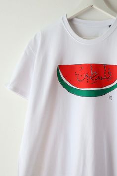 Watermelon cotton t-shirt made with screen printing 🍉. "Palestine" in Arabic calligraphy in the middle, illustration by Anis, Marseille artist. 80% of profits are donated to identified Gazan fundraisers. More info on @de.marseille.a.gaza 🇵🇸 Watermelon T Shirt, Watermelon Tshirt, Watermelon Shirt, In Arabic, Cotton T Shirt, Watermelon, Tee Shirt, Favorite Outfit, Cotton Tshirt