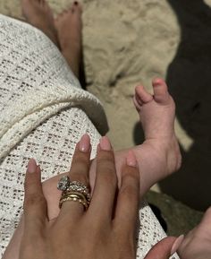 a woman holding her baby's hand while laying down on the ground with it's foot up