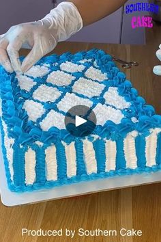 someone in white gloves is decorating a blue and white cake