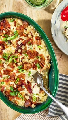 a casserole dish with bacon, green onions and cheese in it on a wooden table