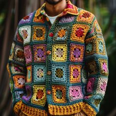 a man wearing a multicolored crocheted jacket and hat with his hands in his pockets