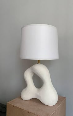 a white lamp sitting on top of a wooden block