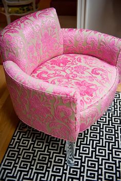 a pink chair sitting on top of a black and white rug