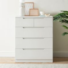 a white dresser sitting next to a potted plant