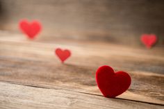 small red hearts are scattered on a wooden surface