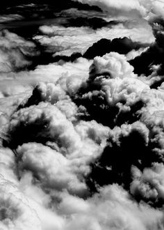 black and white photo of clouds in the sky from an airplane window, looking down