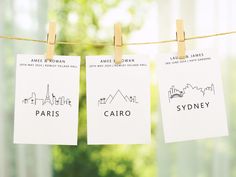 three business cards hanging on a clothes line with the names of paris, sydney and melbourne