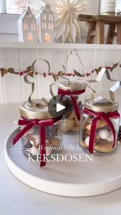 three glass jars filled with cookies on top of a white table next to a red ribbon