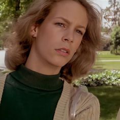 a woman standing in front of a lush green park