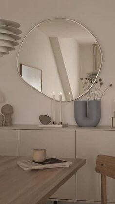 a round mirror on the wall above a wooden table