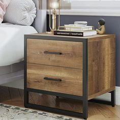 a night stand with two drawers and a lamp next to it on top of a bed