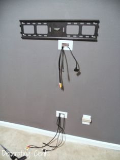 a flat screen tv mounted to the side of a wall with two wires connected to it