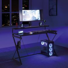 a desk with a computer on it in front of a purple lit room and window