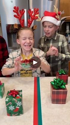 two young boys sitting at a kitchen table with presents in front of them and one boy holding a cookie