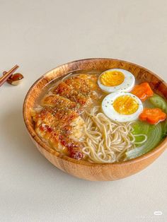 a wooden bowl filled with noodles and eggs