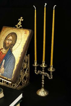 an image of jesus holding a bottle next to three candles and a book on a table