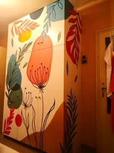 a painting on the side of a cabinet with flowers and leaves painted on it in an orange room