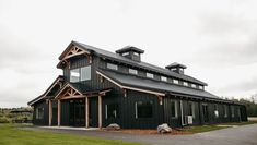 a large black building sitting on top of a lush green field next to a forest