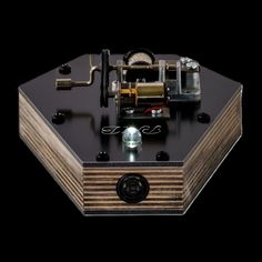 an old fashioned clock sitting on top of a wooden table next to a black background