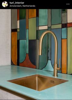 a kitchen sink sitting under a faucet in front of a colorful tile wall