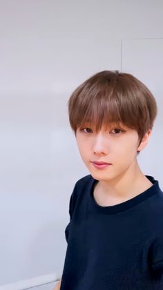 a young man with brown hair wearing a black t - shirt and looking at the camera