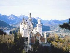 an old castle is surrounded by trees and mountains