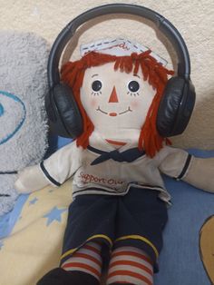 a stuffed doll with headphones on sitting next to a teddy bear