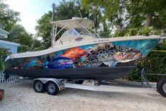 a boat is parked on the trailer in front of a house with fish painted on it