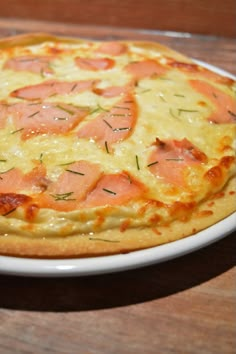 a pizza with ham and cheese on a white plate