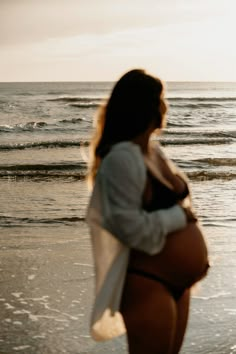 a pregnant woman walking on the beach at sunset