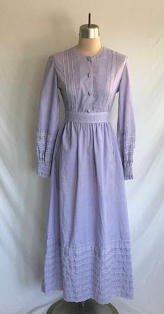 Darling 1970's purple cotton eyelet lace trimmed prairie dress with pockets! Dress is a maxi length with long sleeves, tie back at waist, button down front and buttons that look like jelly beans! Dress zips up the back with a plastic zipper. Dress has a Victorian Gunne Sax look to it and fits easily into the cottagecore style.  Dress is clean and in excellent condition!  No label: appears to have been skillfully handmade!  Measurements: would best fit a modern size XS  Bust= 34" Waist= 25" Hip= Spring Cotton Prairie Dress In Peasant Style, Long Sleeve Cotton Victorian Dress For Spring, Cotton Prairie Dress For Fall Daywear, Cotton Prairie Dresses, Cotton Victorian Dress For Spring, Fitted Cotton Prairie Dress For Daywear, Cotton Victorian Dress For Spring Daywear, Spring Cotton Prairie Dress For Daywear, Cotton Vintage Dress For Fall Daywear