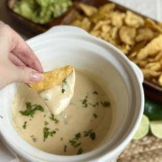 a person dipping tortilla chips into a bowl