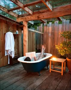 a person laying in a bathtub with their feet up on the tub and reading a book