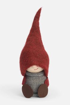 a small doll with a red hat and sweater on it's head, sitting in front of a white background