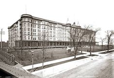 an old black and white photo of a large building in the middle of a park