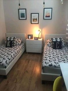 two beds in a room with wooden floors and pictures on the wall above them,