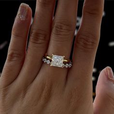 a woman's hand with a diamond ring on top of her finger and the other hand holding an engagement ring