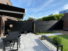 an outdoor patio with table, benches and grass